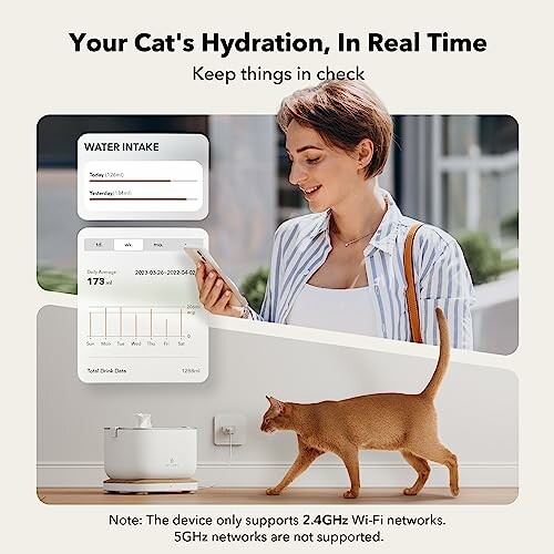 Woman checking cat hydration stats on a device with a cat near a water fountain.